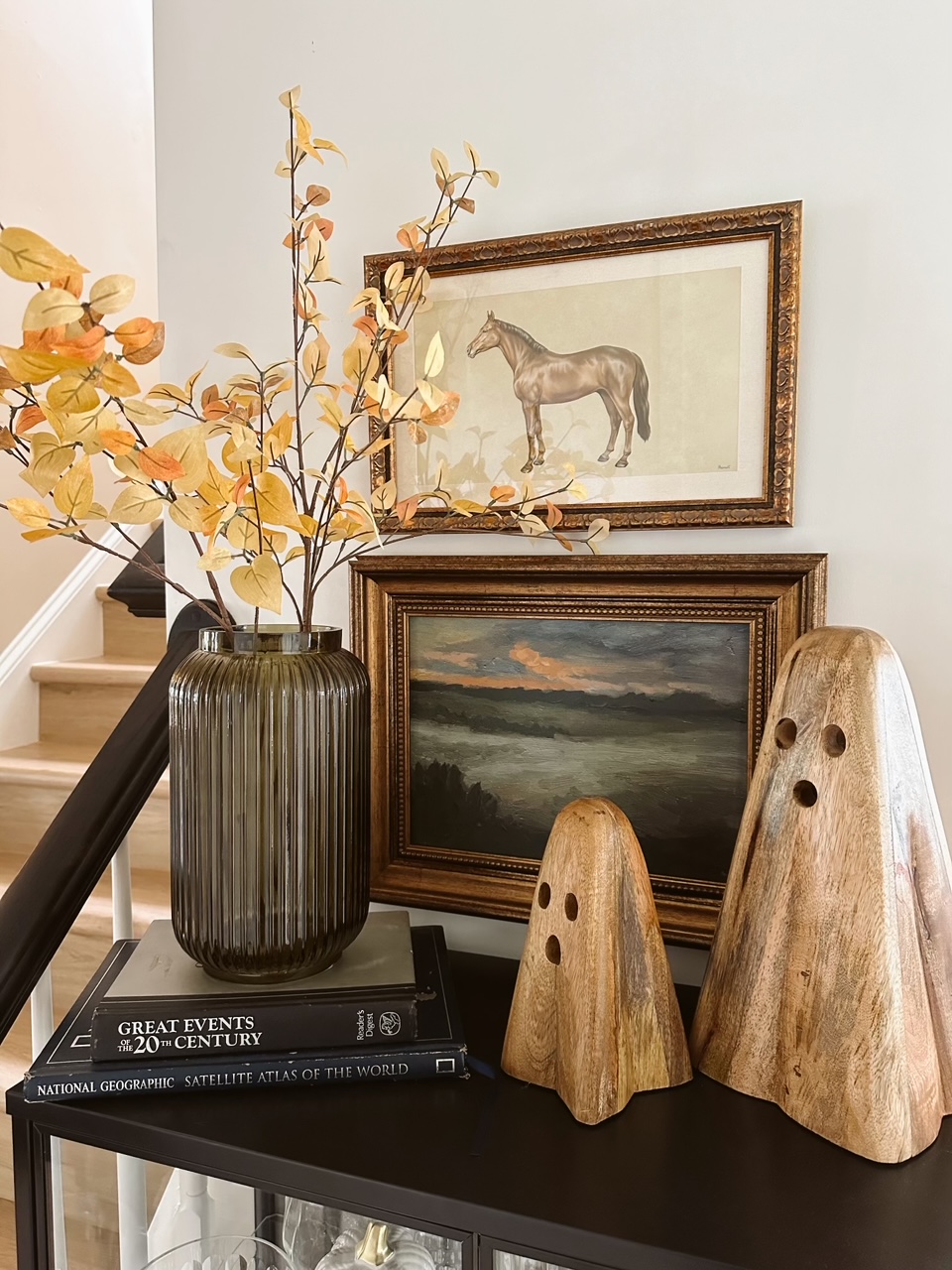 Autumn stems on entry table next to wooden ghosts.